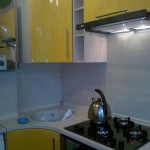 Желтая угловая кухня с варочной панелью с колонкой