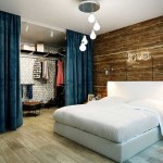 Спальня в стиле лофт. Дерево на стене. Синие шторы. Фото