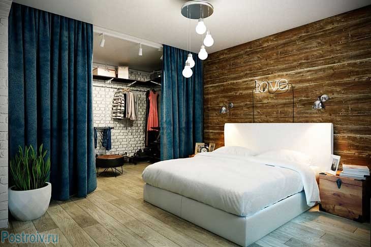 Спальня в стиле лофт. Дерево на стене. Синие шторы. Фото
