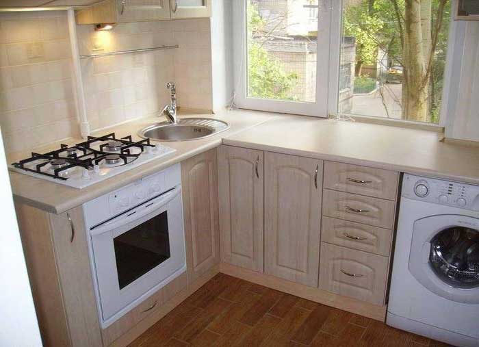 Стиральная машинка на кухне под подоконником